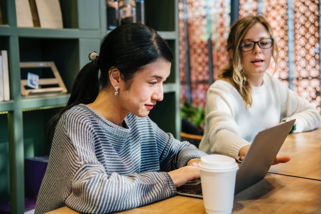 Two women working together over coffee with a lapton