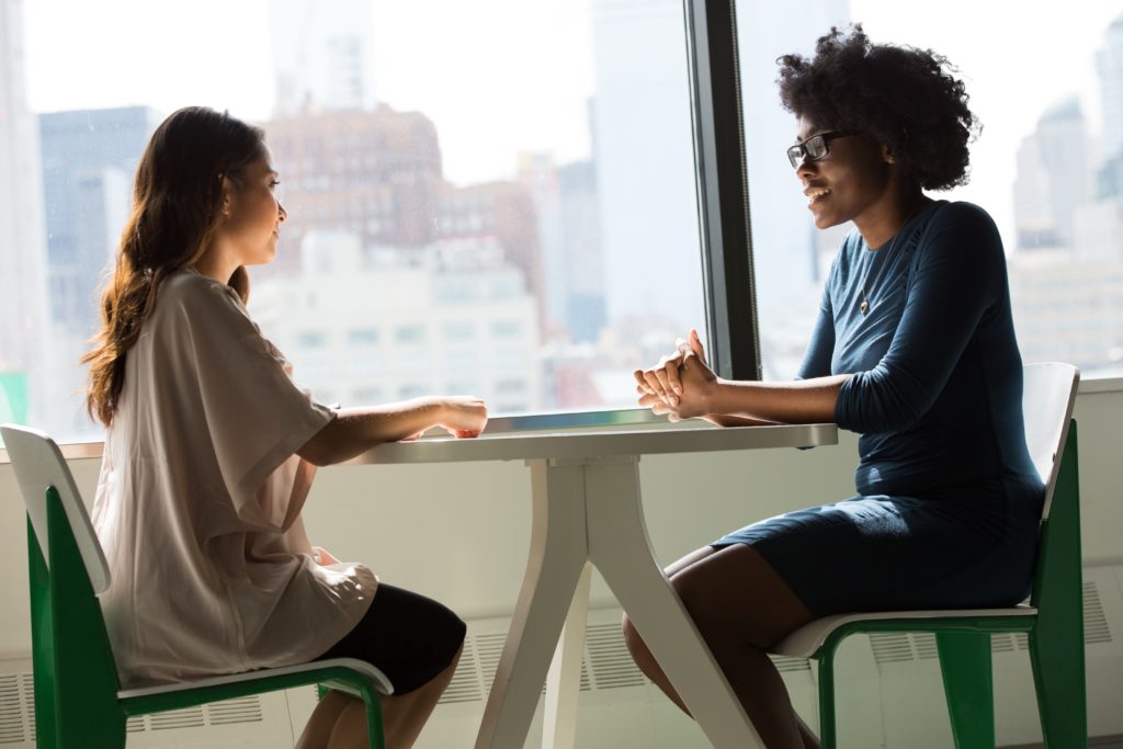 Two women at table discussing leadership.