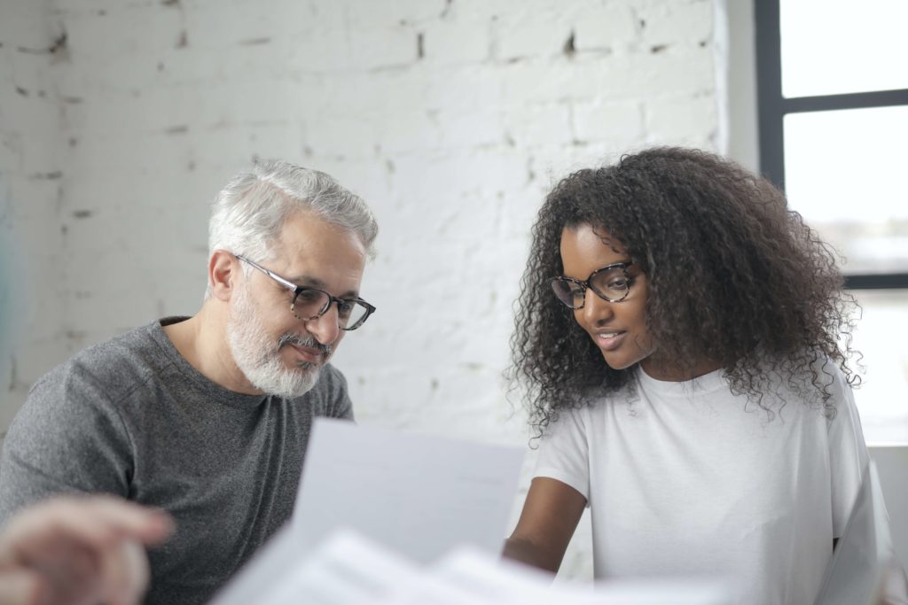 white man with beard speaking to black woman at work