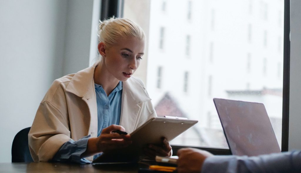 White woman looking at clipboard in office